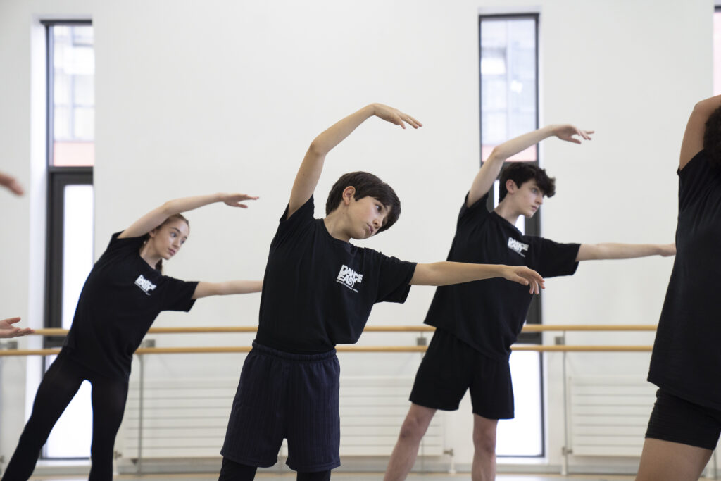 Three dancers leaning to the right with one of their arms curved above their head.