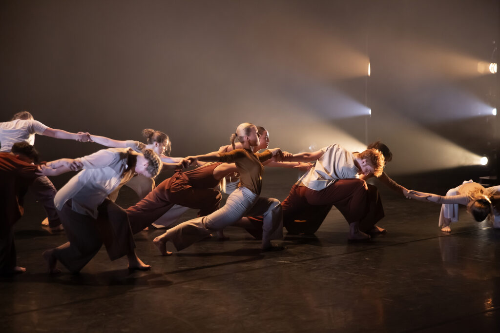 CAT students linked together to create a line across the stage, all at different levels.